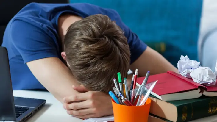 شاب يعاني من الإرهاق الدراسي وقلة النوم، يمثل تأثير قلة النوم على التحصيل الدراسي