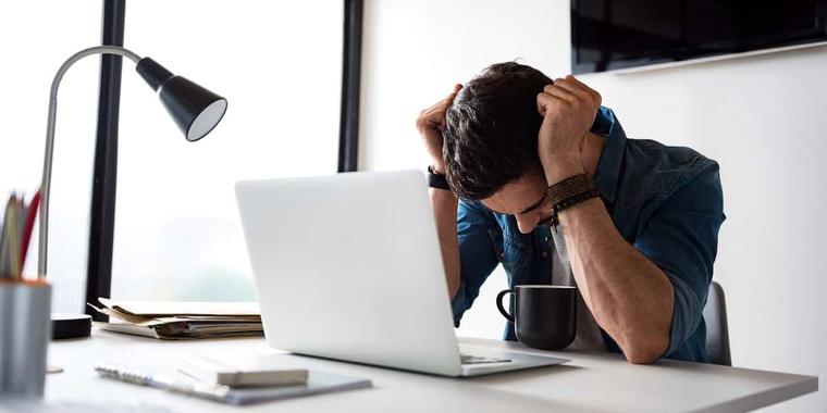 رجل مرهق ومتوتر أمام لابتوب، يمثل تحديات ريادة الأعمال وأخطاء رواد الأعمال التي قد تؤدي إلى فشل المشاريع الناشئة.