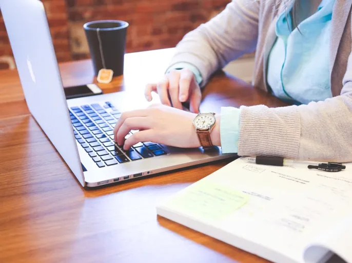 يدان تعملان على لابتوب، تمثل التعلم عبر الإنترنت وكيف تحافظ على تركيزك أثناء الدراسة