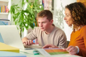 طالب يتلقى التعلم المخصص والتكيفي على حاسوب محمول بمساعدة موجهة