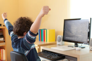 طفل يحتفل بالنجاح الدراسي في التعليم الإلكتروني والتعلم عن بُعد من المنزل