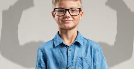 طفل يبتسم مع ظل أذرع قوية يمثل بناء شخصية قوية لدى الأطفال وتنمية قوتهم الكامنة